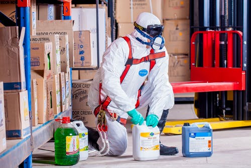 Man with mask bending down over hazardous chemicals in a building